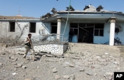An Afghan security guard inspects the site of a truck bombing attack in Logar province, east of Kabul, Afghanistan, Thursday, Aug. 6, 2015.