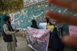 FILE - A member of the Taliban speaks with women protesters as another tries to block the view of the camera with his hand, during a demonstration held outside a school in Kabul, Afghanistan, Sept. 30, 2021.
