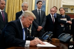 White House chief strategist Steve Bannon (far right) is among the top policy advisers present as President Donald Trump signs an executive order in the Oval Office, Jan. 23, 2017.