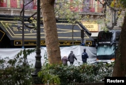 People walk past the screened-off facade of the Bataclan Cafe and its adjoining concert hall the day after a series of deadly attacks in Paris, Nov. 14, 2015.