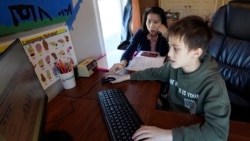 Kim Horrigan, left, sits with her son Conor Horrigan, as Conor does math homework at their home, in Quincy, Tuesday, April 13, 2021