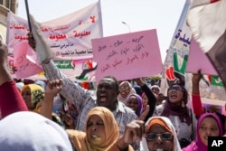 Protesters carry posters in Arabic that say, "Freedom, justice, and peace, and the revolution is the choice of the people," at the sit-in outside the military headquarters, in Khartoum, Sudan, May 2, 2019.