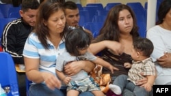 FILE - Mothers and children wait to be assisted by volunteers in a humanitarian center in the border town of McAllen, Texas, June 15, 2018.