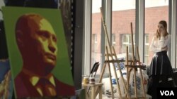 An activist is seen talking on her phone at the office of pro-Kremlin youth group SET (Network). To her left is a portrait of Russian President Vladimir Putin. (VOA video screengrab)