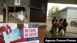 FILE - A security official examines workers' COVID-19 vaccination passes in Benin City Nigeria, Sept. 16, 2021.
