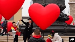 FILE - Families with young children pose for photos in Beijing, Feb. 13, 2021. Struggling with an aging population and declining birth rates, China is trying to shift its population policies to avert a demographic crisis.