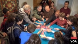 People of all ages are dismantling the sand mandala, an integral part of the ancient ritual art. (VOA/ J. Soh)