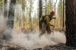 Firefighter Garrett Suza, with the Chiloquin Forest Service, mops up a hot spot on the North East side of the Bootleg Fire, July 14, 2021, near Sprague River, Ore.