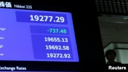 A man is seen behind an electronic board showing the Nikkei average after the New Year's opening ceremony at the Tokyo Stock Exchange, held to wish for the success of Japan's stock market, in Tokyo, Jan. 4, 2019. 