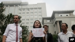 FILE - Li Wenzu, center, wife of imprisoned lawyer Wang Quanzhang, holds a paper that reads "Release Liu Ermin" as she and supporters of a prominent Chinese human rights lawyer and activists stage a protest outside the Tianjin No. 2 Intermediate People's Court.