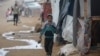 A Palestinian child runs to shelter from the rain at the Nuseirat refugee camp in the Gaza Strip on Dec. 20, 2024.