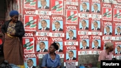 Women, selling charcoal, chat in front of the ruling FRELIMO party election posters in the capital, Maputo, Mozambique August 31, 2019. REUTERS/Siphiwe Sibeko