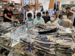 Children wear protective face masks as they look at clothes in a shop ahead of the Eid al-Adha celebrations amid the coronavirus disease (COVID-19) pandemic, in Misrata, Libya, July 28, 2020.