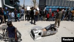 A boy stands next to the remains of a missile, in Douma, near Damascus, Syria, April 16, 2018.