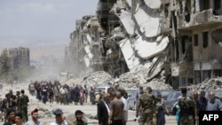 Les forces pro-gouvernementales se tiennent dans la rue détruite de Thalateen, dans la banlieue sud de la capitale, Damas, le 24 mai 2018.