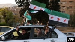 People celebrate with the Syrian opposition flag, in Damascus, Dec. 10, 2024. 