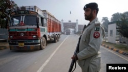 FILE - A paramilitary soldier stands guard as a truck crosses into Pakistan from India at the Wagah border, Nov. 4, 2011. 