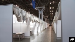 In this March 27, 2020 photo provided by Office of Governor Andrew M. Cuomo, makeshift hospital rooms stretch out along the floor at the Jacob Javits Convention Center in New York.