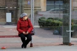 A health care worker waits for a bus outside a hospital amid the coronavirus disease (COVID-19) outbreak in Boston, Massachusetts, April 10, 2020.