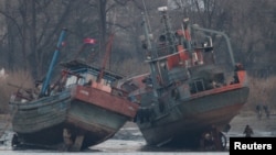 A cargo boat (R) is seen on the bank of the Yalu River in Sinuiju, opposite the Chinese border city of Dandong, March 14, 2016.
