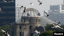 FILE - Doves fly over Peace Memorial Park with the Atomic Bomb Dome in the background, at a ceremony in Hiroshima, Japan, Aug. 6, 2015. 