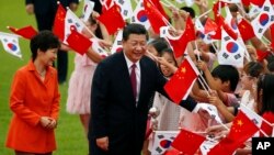Chinese President Xi Jinping, right, and South Korean President Park Geun-hye, left, greet children at the Presidential Blue House in Seoul, South Korea, July 3, 2014.