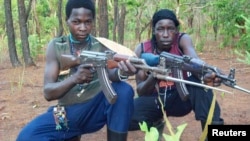 FILE - Fighters loyal to the Lord's Resistance Army pose with their rifles inside the forest near River Mbou in the Central African Republic in this handout picture dated April 4, 2012.