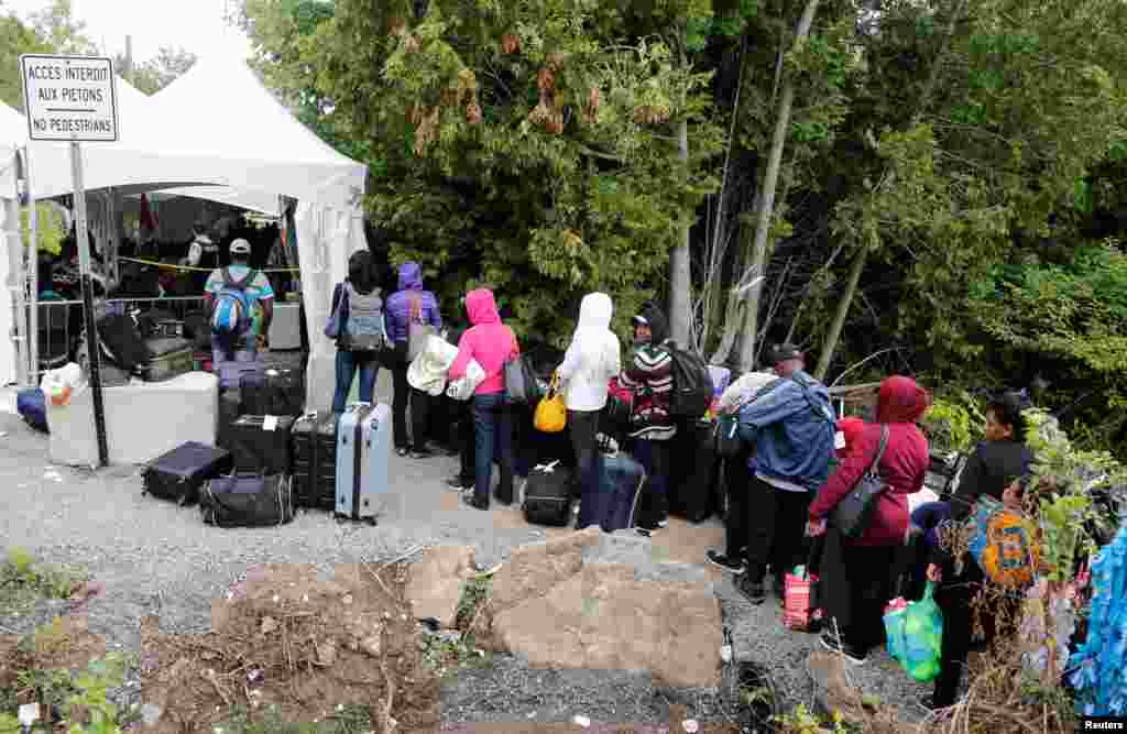 A line of asylum seekers who said they were from Haiti wait to enter into Canada from Roxham Road in Champlain, New York, Aug. 7, 2017.