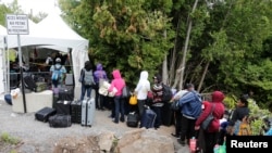 A line of asylum seekers who said they were from Haiti wait to enter into Canada from Roxham Road in Champlain, New York, Aug. 7, 2017.