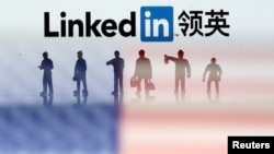 FILE - Small toy figures are seen between displayed U.S. flag and Linkedin logo in this illustration picture.