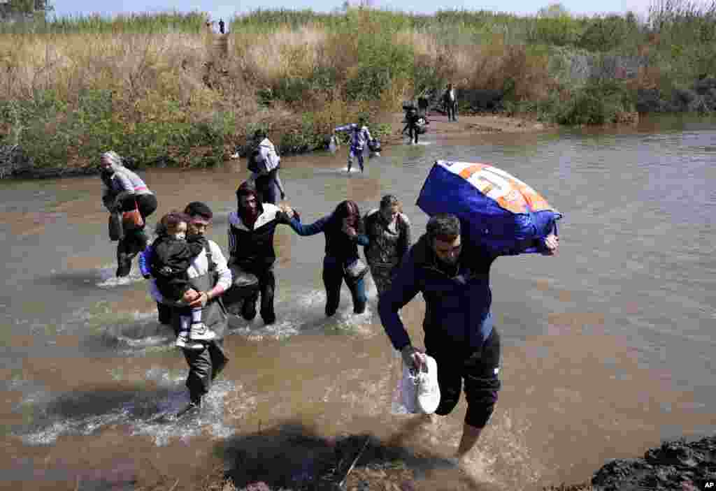Syrian families who fled the clashes in the country cross a river marking the border between Syria and northern Lebanon near the village of Heker al-Daher in Akkar province, Lebanon.