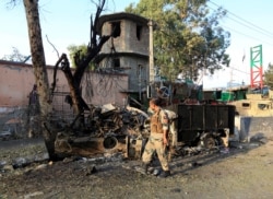 FILE - A member of Afghan security forces inspects the site of an attack on a jail compound in Jalalabad, Aug. 3, 2020.