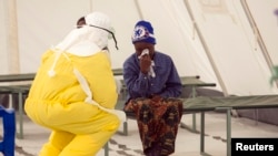 A health worker in protective gear addresses a suspected Ebola patient in a quarantine zone at a Red Cross facility in the eastern Sierra Leone town of Koidu. 