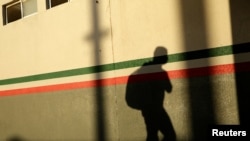 La sombra de un migrante mexicano se posa sobre uno de los muros de una oficia del Instituto Nacional de Migración, en Ciudad Juárez, México, tras ser deportado de Estados Unidos el 29 de abril de 2020.