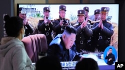 FILE - People watch a TV screen showing a file image of North Korean leader Kim Jong Un during a news program at the Seoul Railway Station in Seoul, South Korea, March 21, 2020. The North conducted another apparent missile test early March 29.