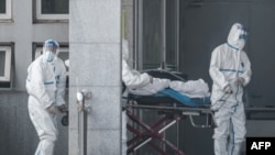 Des membres du personnel médical transportent un patient à l'hôpital de Jinyintan, où des patients infectés par un mystérieux virus semblable au SRAS sont traités, à Wuhan dans la province centrale du Hubei en Chine le 18 janvier 2020. (Photo by STR / AFP)