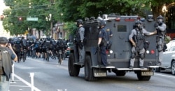 Seattle Police ride on a vehicle behind bicycle police during a Black Lives Matter protest march, July 25, 2020, in Seattle.