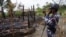 FILE - A Myanmar border guard police officer takes pictures at the remains of a burned house in Tin May village, northern Rakhine state, Myanmar.