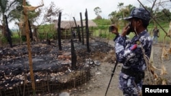 FILE - A Myanmar border guard police officer takes pictures of the remains of a burned down house in Tin May village, northern Rakhine state, Myanmar, July 13, 2017.
