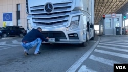 Vozač postavlja stiker na registarske tablice kamiona, na prelazu Merdare na Kosovu, 4. oktobra 2021.