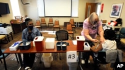 Nurse Marianne Williams administers a COVID-19 vaccine to a woman as a coworker looks on at the county health department in Tuskegee, Ala., Jan. 25, 2021. 