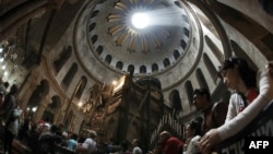 FILE - A picture taken with a fisheye lens shows Christian worshippers praying inside the Church of the Holy Sepulchre as rays of sunlight come through the top rotunda in Jerusalem’s Old City during the Good Friday procession on March 25, 2016.