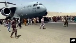 Stotine ljudi trči duž piste pored američkog vojnog transportnog aviona C-17, dok se on kreće pistom u Kabulu, Afganistan, 16. avgusta 2021.