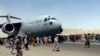 Hundreds of people run alongside a U.S. Air Force C-17 transport plane as it moves down a runway of the international airport, in Kabul, Afghanistan, Aug.16. 2021.
