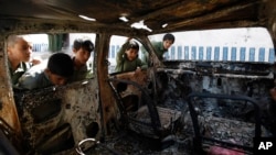 FILE - Yemeni boys look at a vehicle destroyed during a police raid on an al-Qaida militant hideout in the Arhab region, north of Sanaa, Yemen, May 27, 2014.