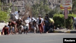 People seek shelter from gunfire at an army base in Yemen's southern port city of Aden, March 25, 2015. 