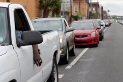 People line up for food in a vehicle line that stretched one mile, to receive food at a food distribution point for people economically impacted by the coronavirus pandemic, organized by New Orleans City Councilman Jay Banks, in New Orleans.