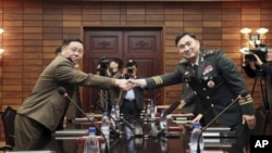 Jenderal Korea Selatan Kim Do-gyun (kanan) berjabat tangan dengan Letnan Jenderal An Ik San dari Korea Utara, di kota perbatasan Panmunjom, Korea Utara, 26 Oktober 2018. (Korea Pool / Yonhap melalui AP)