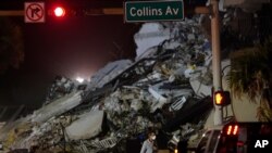 A man walks beside the rubble as rescue efforts continue where a wing of a 12-story beachfront condo building collapsed, June 24, 2021, in the Surfside area of Miami.