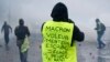 Seorang demonstran mengenakan jaket kuning bertuliskan “Macron, pencuri, pembohong, penjahat, pergi, warga mengusir Anda” dekat Champs-Elysees dalam unjuk rasa di Paris, Sabtu, 1 Desember 2018.